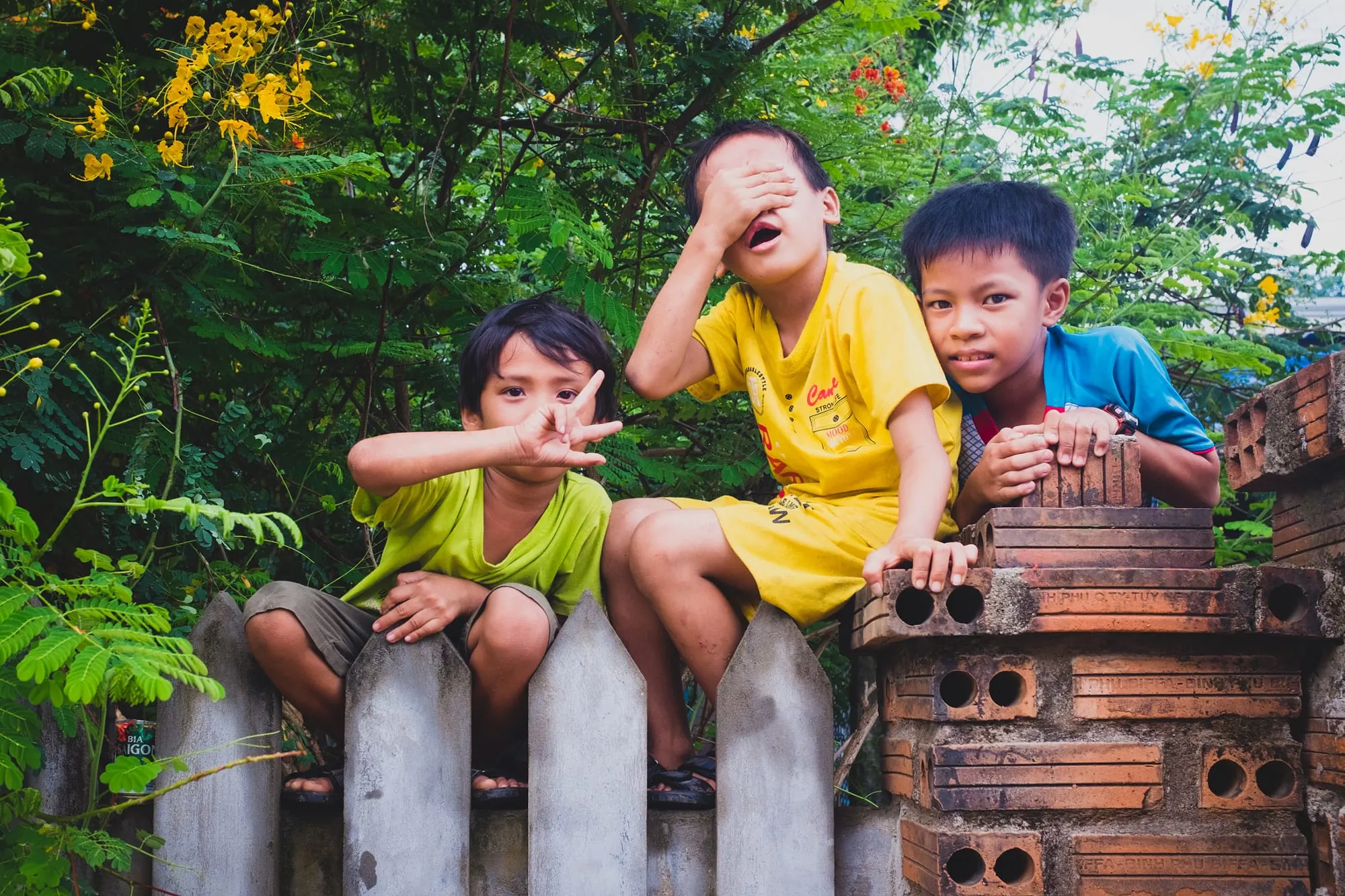 Ba cậu bé ngồi trên bờ rào gạch, cười đùa vui vẻ