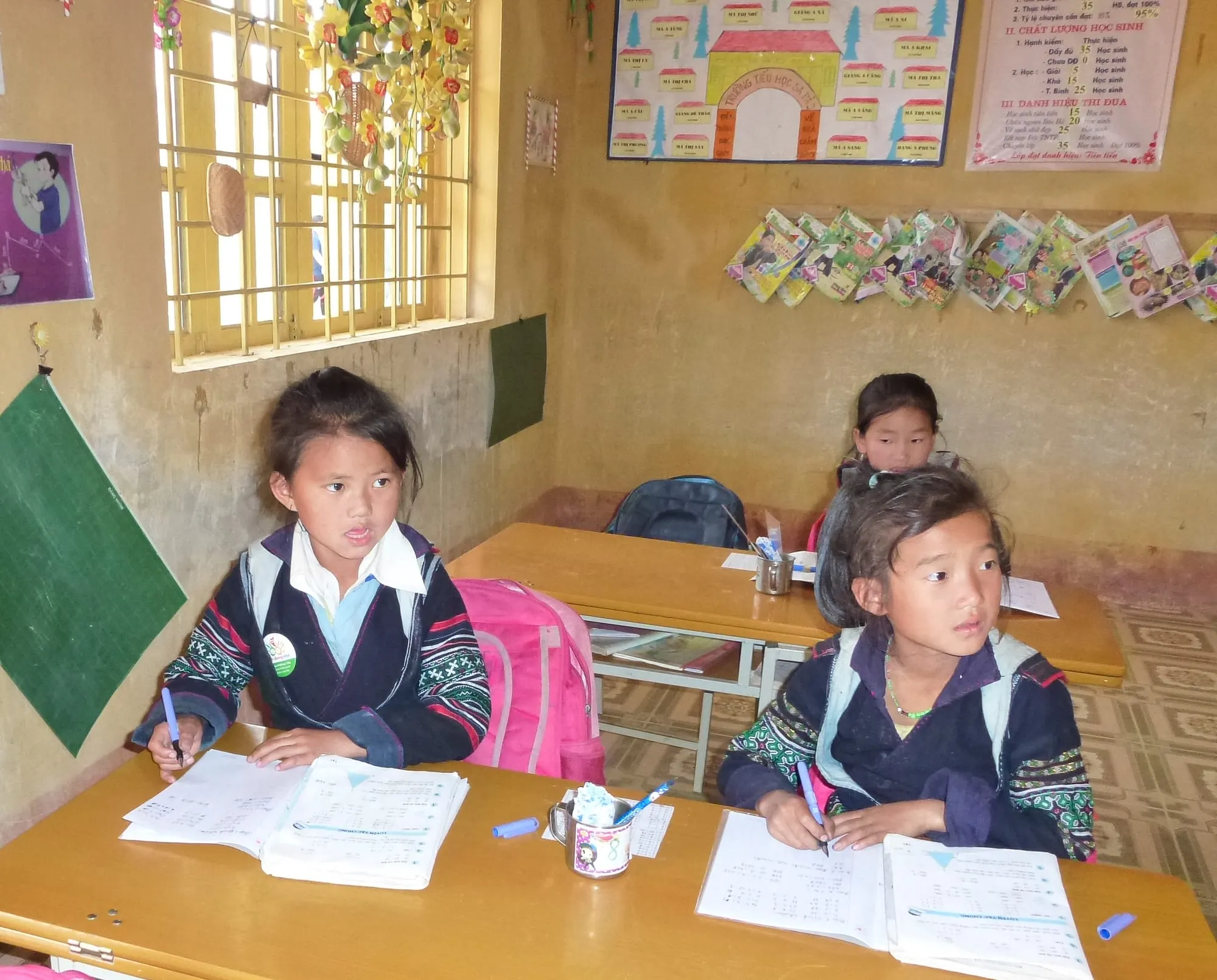 Two Hmong primary-school girls writing in their notebooks in a classroom in Sa Pa, Lào Cai