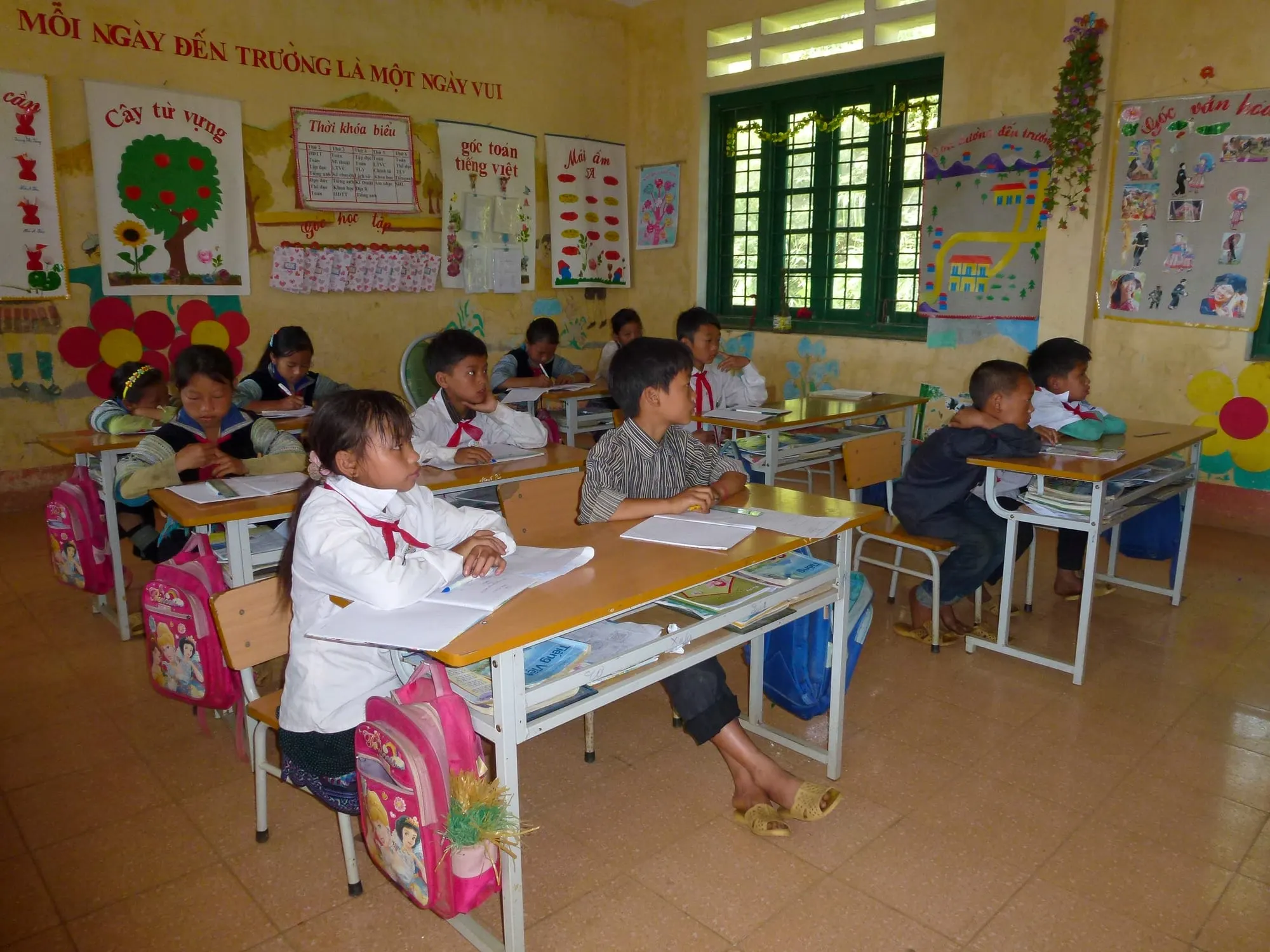 Lớp học tiểu học vùng cao với học sinh ngồi bàn, balo đặt cạnh ghế
