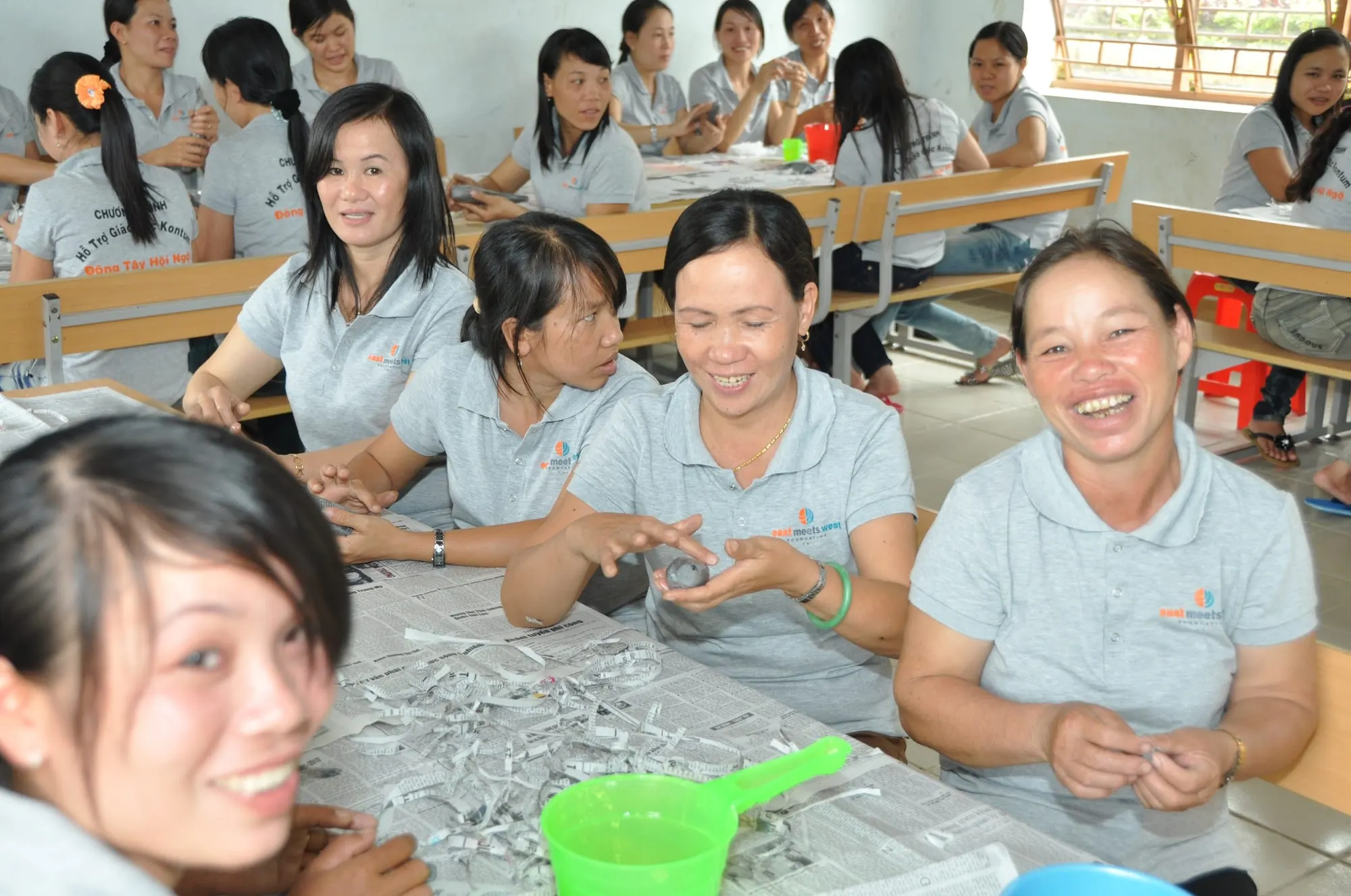 Preschool teachers laughing as they make teaching materials together during a training session in Kon Tum