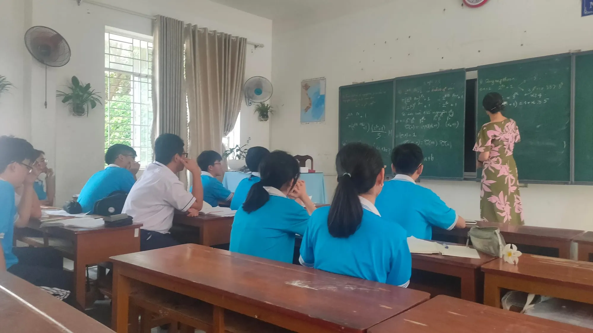 Học sinh trong giờ học, cô giáo giảng bài trên bảng